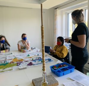 Gruppe sitzt um Spielbrett vor dem Carbometer